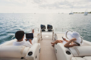 Handsome Man And Woman On Deck Of Yacht With Mobile Phone And Laptop