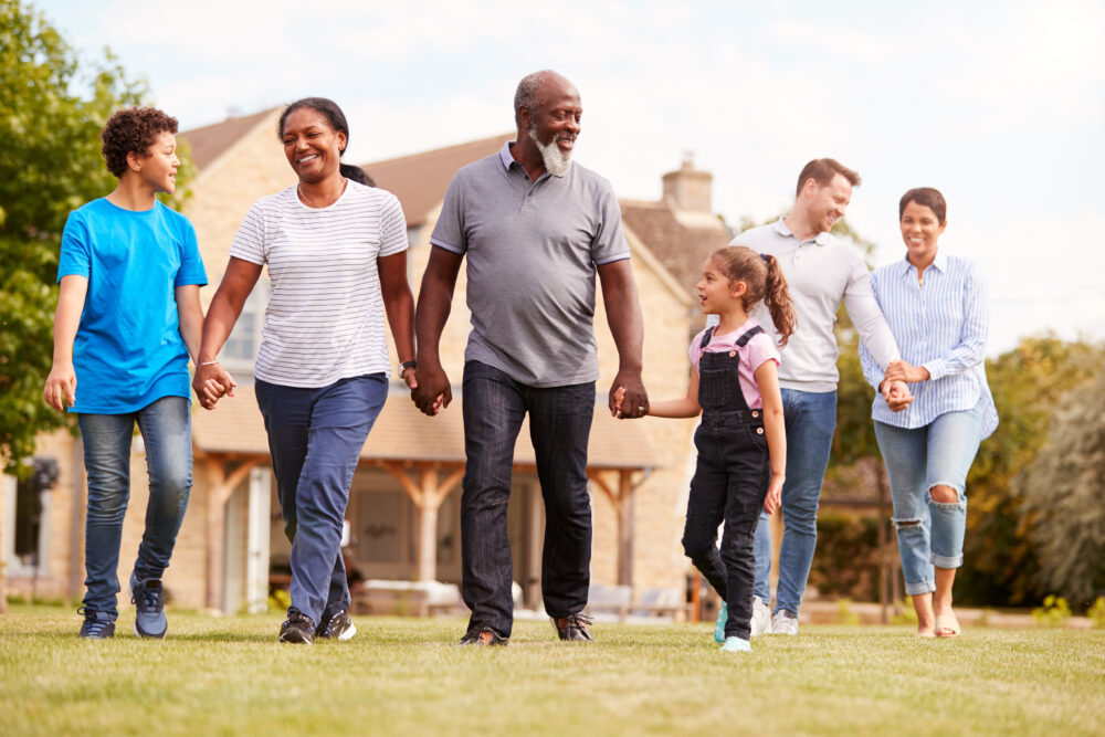 Smiling Multi Generation Mixed Race Family Walking In Garden At Home